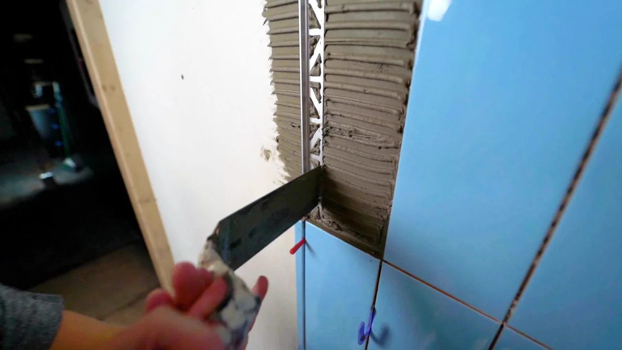 Applying tile adhesive before installing a metal tile edge trim