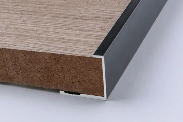 J-shaped aluminum trim covering the edge of a wood panel