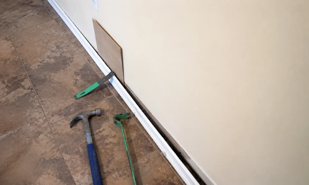 Using a protective wooden block while levering a skirting board from the wall