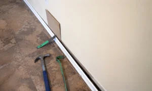 Using a protective wooden block while levering a skirting board from the wall