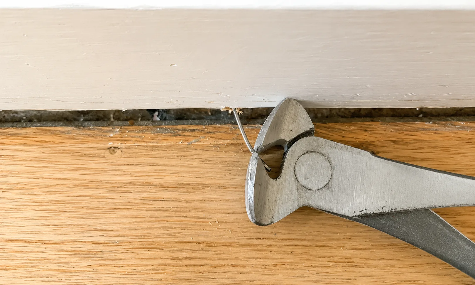 Removing a remaining nail from the back of a skirting board with pliers