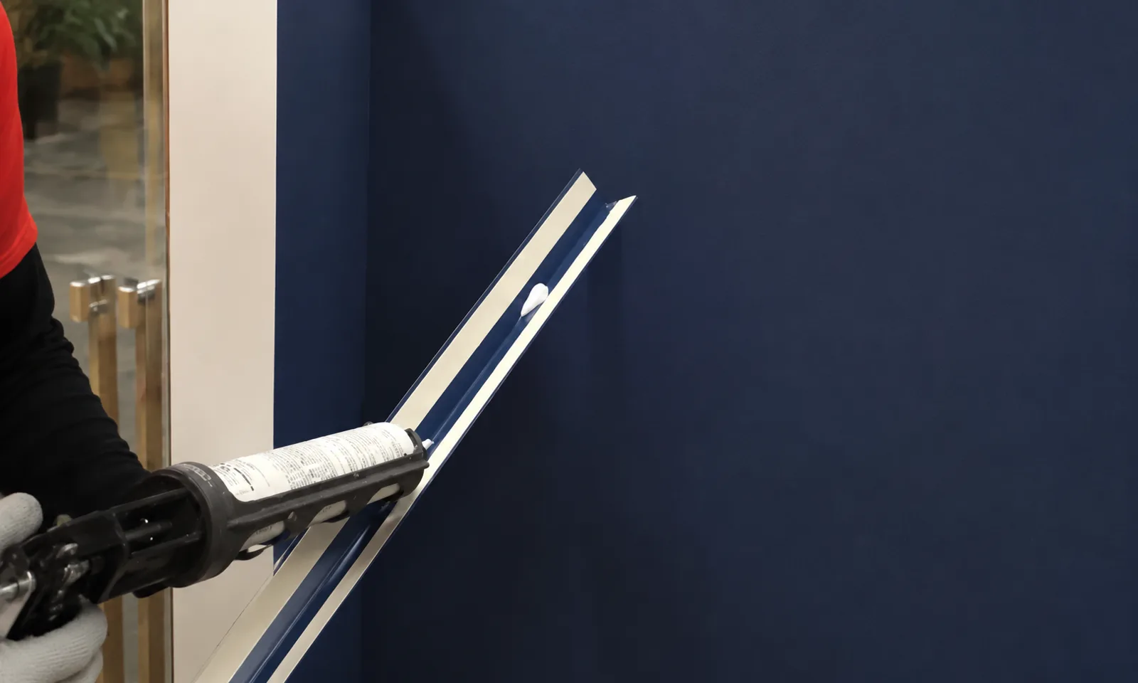 Applying construction adhesive to a surface-mounted metal corner trim