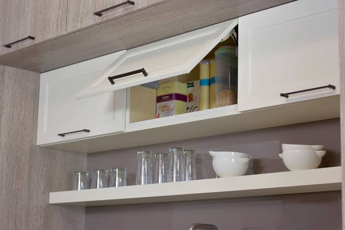 Kitchen cabinet handles placed near the lower corner of upper cabinet doors