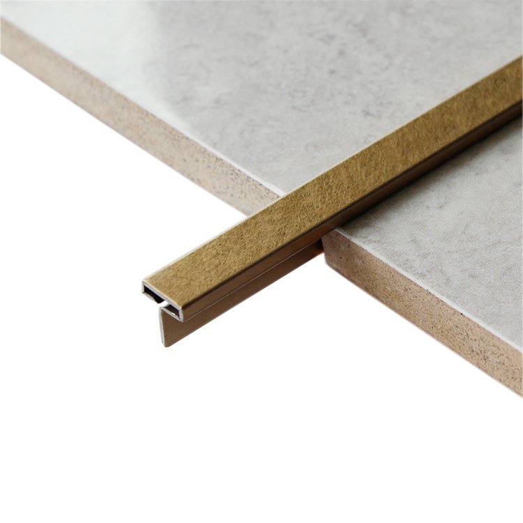 Brushed bronze stainless steel tile edge trim profile between ceramic tiles
